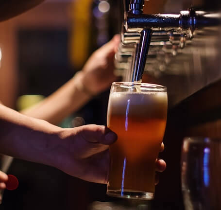 Person pouring a draught beer in a glass